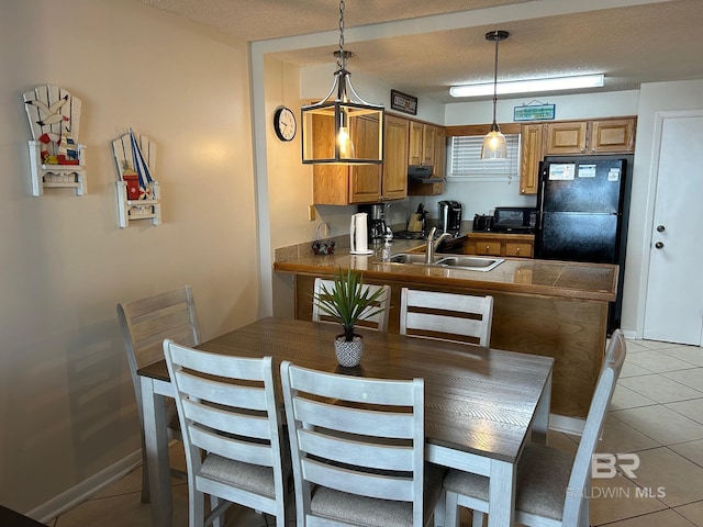 kitchen with kitchen peninsula, pendant lighting, a textured ceiling, light tile patterned floors, and black appliances