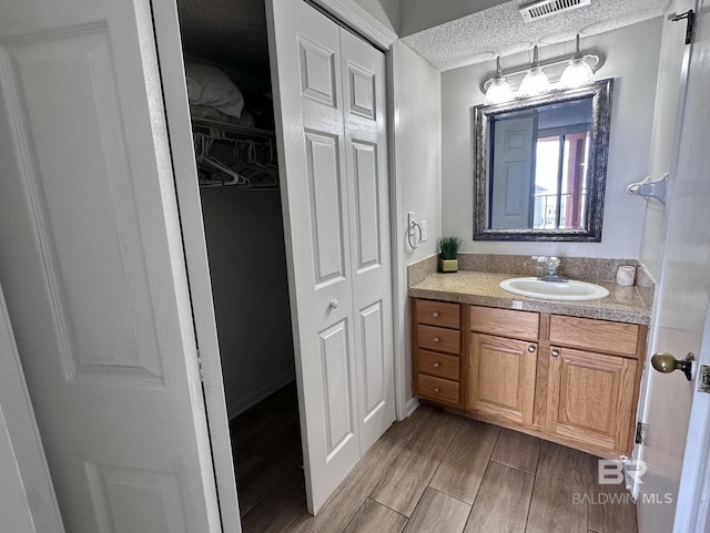 633 W Beach Blvd Unit 303, Gulf Shores, AL 36542 - bathroom with a closet, vanity, a textured ceiling, and wood finished floors