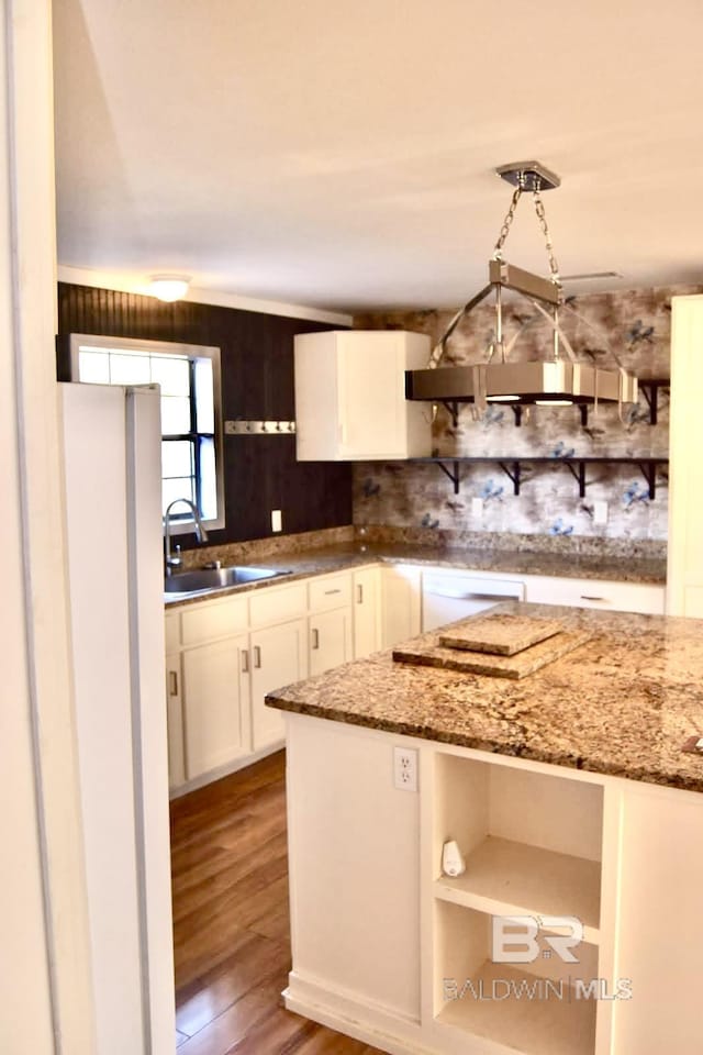 kitchen with dark stone countertops, sink, decorative light fixtures, and white cabinets