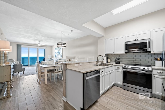 kitchen with sink, kitchen peninsula, stainless steel appliances, and white cabinets