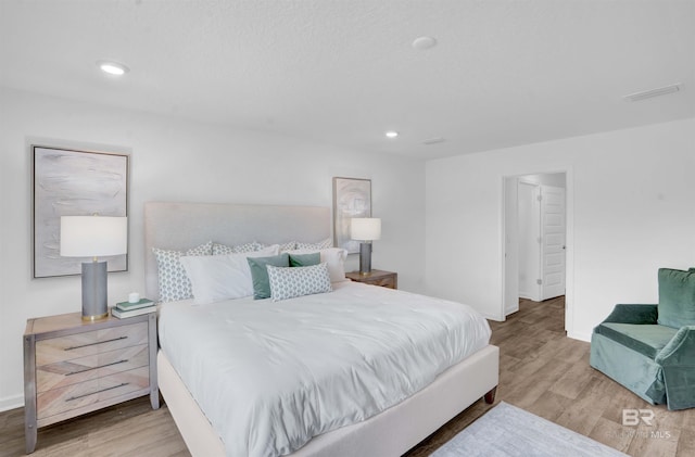 bedroom with baseboards, visible vents, wood finished floors, and recessed lighting