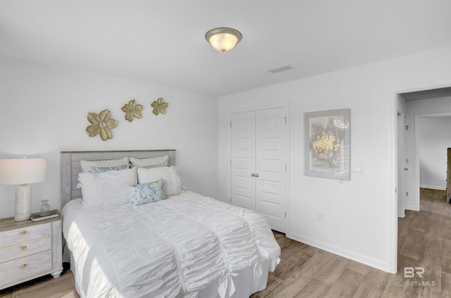 bedroom with a closet, wood finished floors, and baseboards