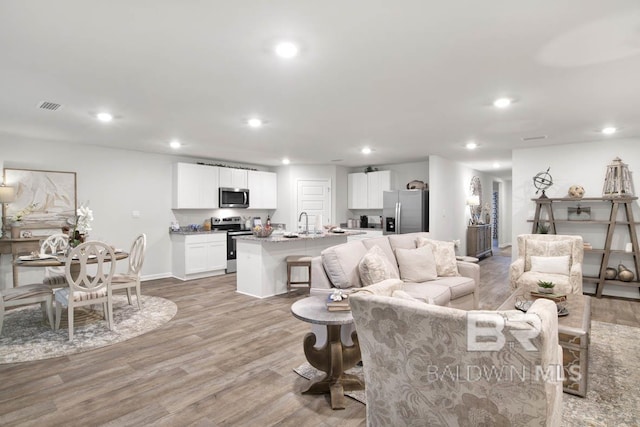 living area with baseboards, light wood finished floors, visible vents, and recessed lighting