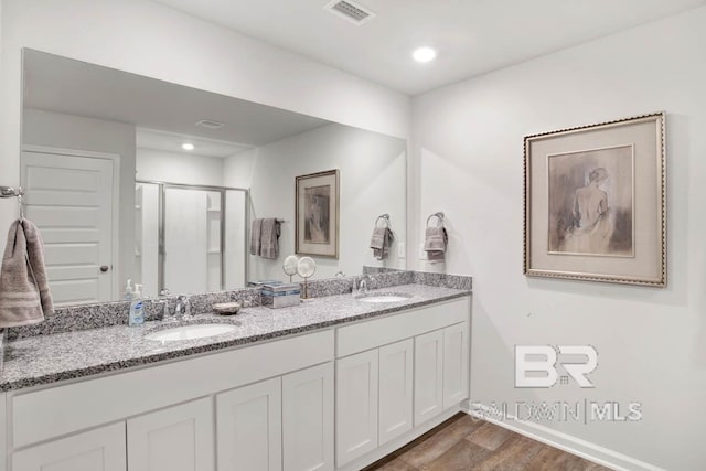 full bath featuring a stall shower, visible vents, a sink, and wood finished floors