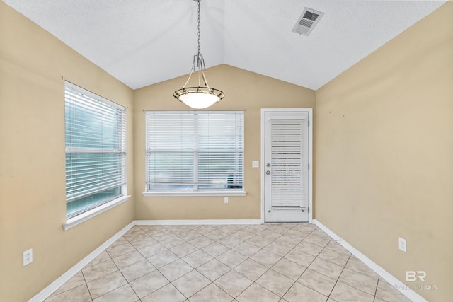 unfurnished dining area with light tile patterned floors, a wealth of natural light, and vaulted ceiling