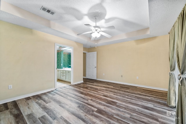 spare room featuring a tray ceiling, ceiling fan, hardwood / wood-style floors, and a textured ceiling