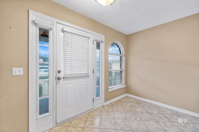 doorway to outside featuring light tile patterned floors and a textured ceiling