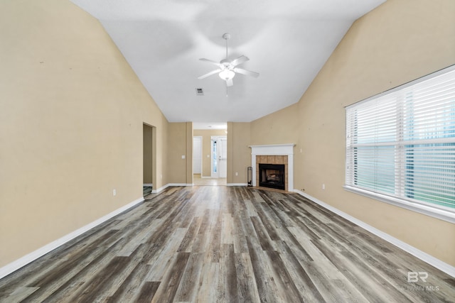 unfurnished living room featuring a tile fireplace, wood-type flooring, vaulted ceiling, and ceiling fan