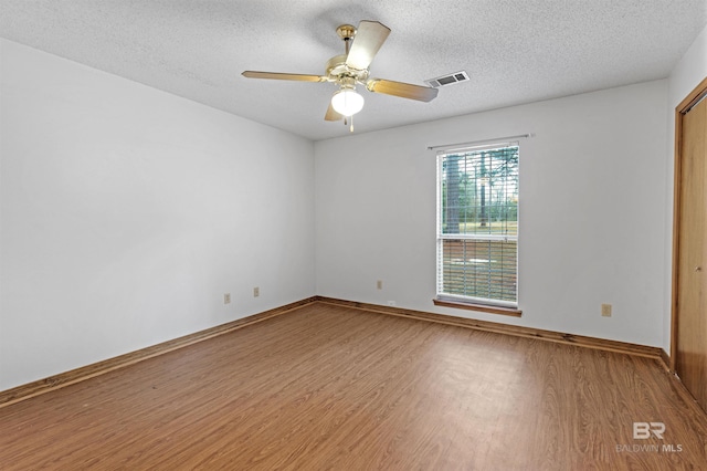 empty room featuring visible vents, baseboards, and wood finished floors