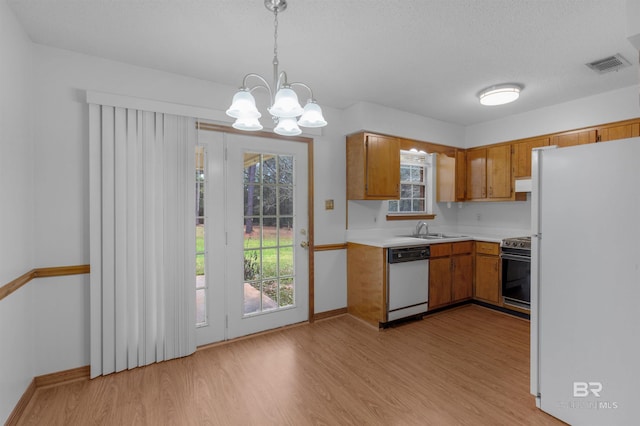 kitchen with light countertops, white appliances, a sink, and brown cabinets