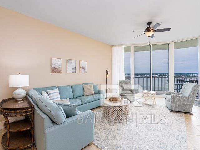 living room featuring tile patterned flooring, expansive windows, ceiling fan, and a water view