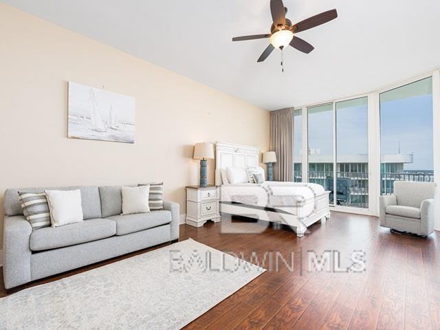 bedroom featuring access to exterior, ceiling fan, dark wood-type flooring, and a wall of windows