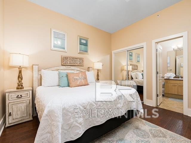 bedroom with ensuite bath, a closet, and dark hardwood / wood-style floors