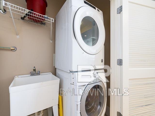 clothes washing area with sink and stacked washer and dryer