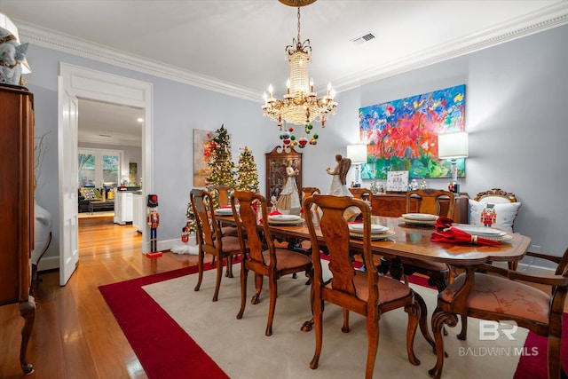 dining area featuring hardwood / wood-style floors, an inviting chandelier, and crown molding