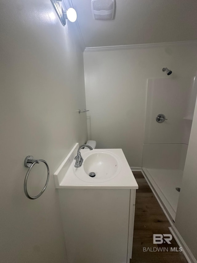 bathroom with ornamental molding, vanity, hardwood / wood-style floors, and a shower