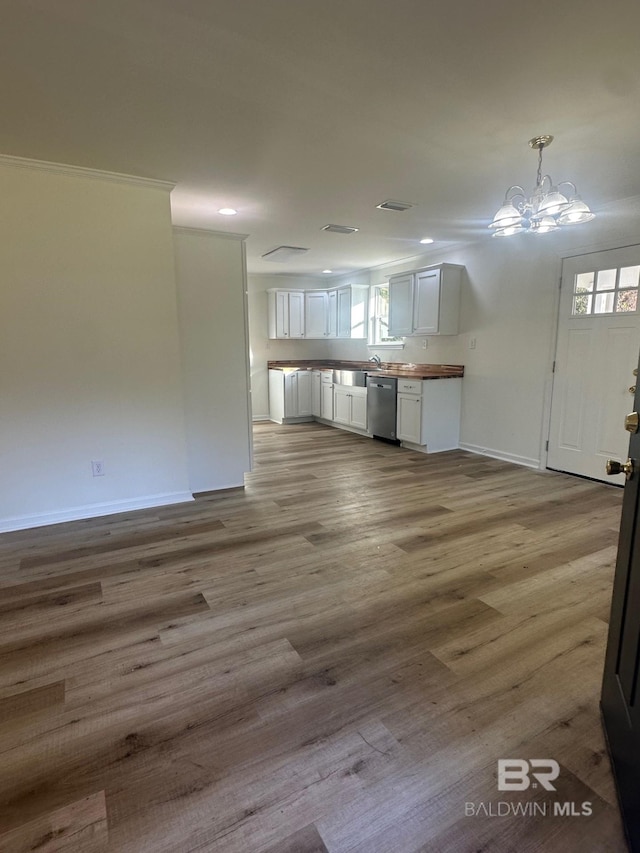 interior space with white cabinetry, stainless steel dishwasher, an inviting chandelier, and light hardwood / wood-style flooring