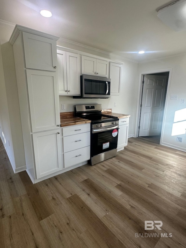 kitchen with stainless steel appliances, wooden counters, white cabinets, and light wood-type flooring