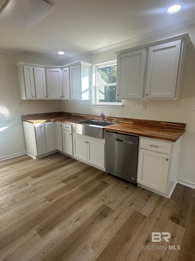 kitchen featuring butcher block countertops, sink, dishwasher, white cabinetry, and light hardwood / wood-style floors