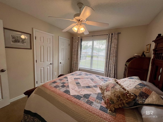 bedroom with carpet flooring, multiple closets, and ceiling fan