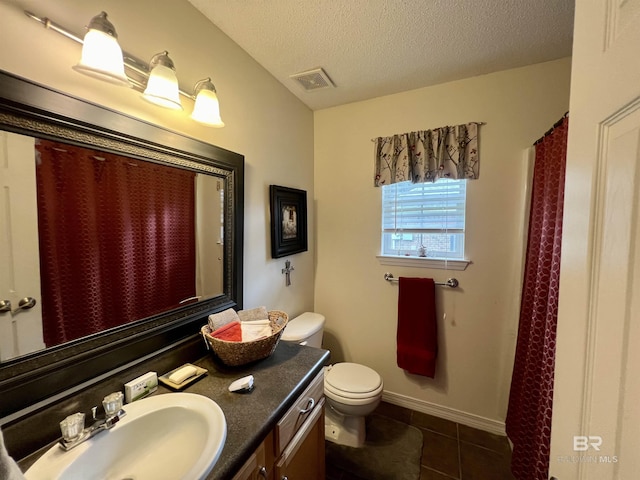 bathroom featuring toilet, a textured ceiling, tile patterned floors, and vanity