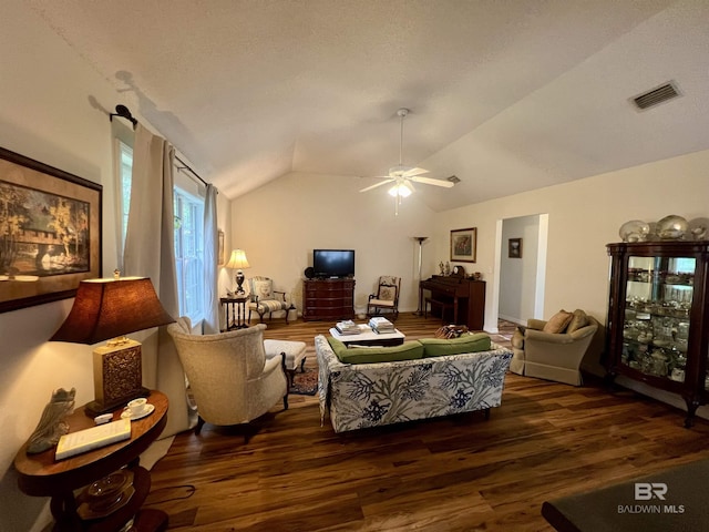 living room featuring ceiling fan, dark wood-type flooring, lofted ceiling, and a textured ceiling