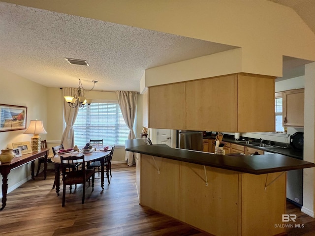 kitchen featuring decorative light fixtures, light brown cabinets, a kitchen bar, kitchen peninsula, and a chandelier