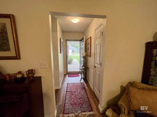 hallway with a textured ceiling and hardwood / wood-style floors