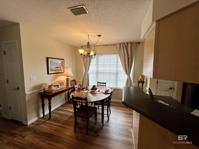 dining space with a textured ceiling, a notable chandelier, and dark hardwood / wood-style floors