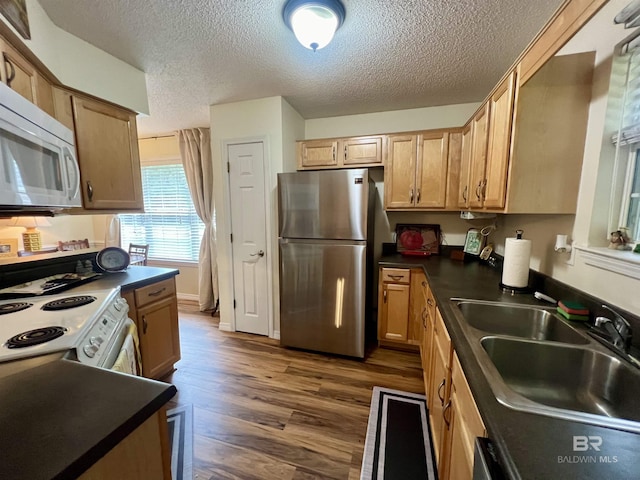 kitchen featuring white appliances, dark wood-type flooring, a textured ceiling, and sink