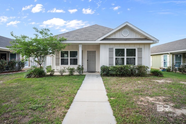 view of front of home featuring board and batten siding, a front lawn, and roof with shingles