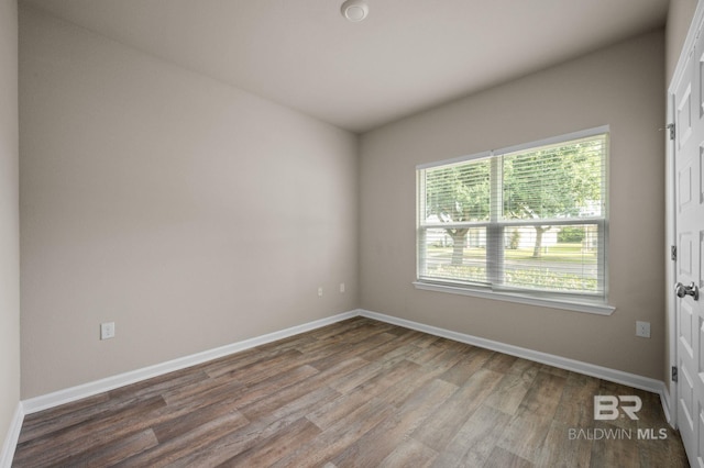 spare room featuring wood finished floors and baseboards