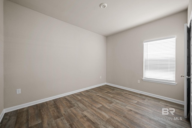 spare room with dark wood-style floors, baseboards, and a smoke detector