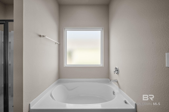 full bathroom with a bath, a textured wall, and a shower with door