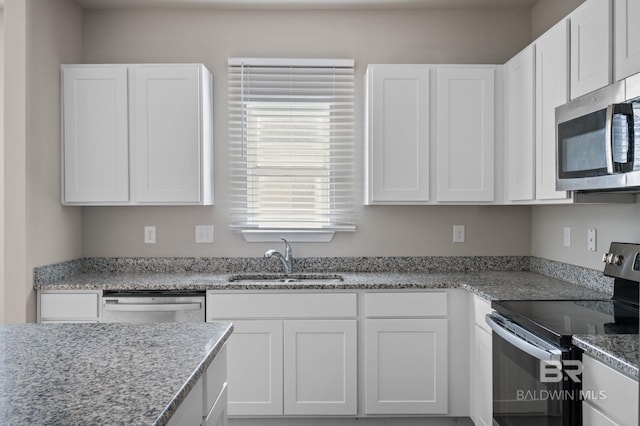 kitchen with appliances with stainless steel finishes, a sink, white cabinets, and light stone countertops