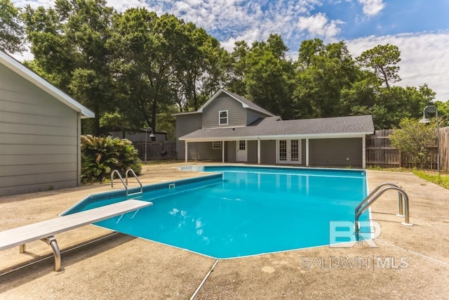 view of swimming pool with a patio, fence, a diving board, french doors, and a fenced in pool