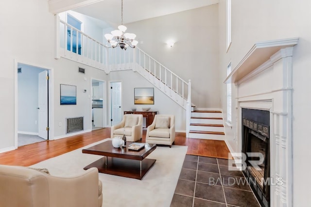 living area featuring dark wood finished floors, a fireplace, a notable chandelier, visible vents, and stairway