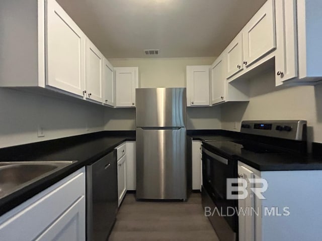 kitchen with dark hardwood / wood-style flooring, white cabinetry, and stainless steel appliances