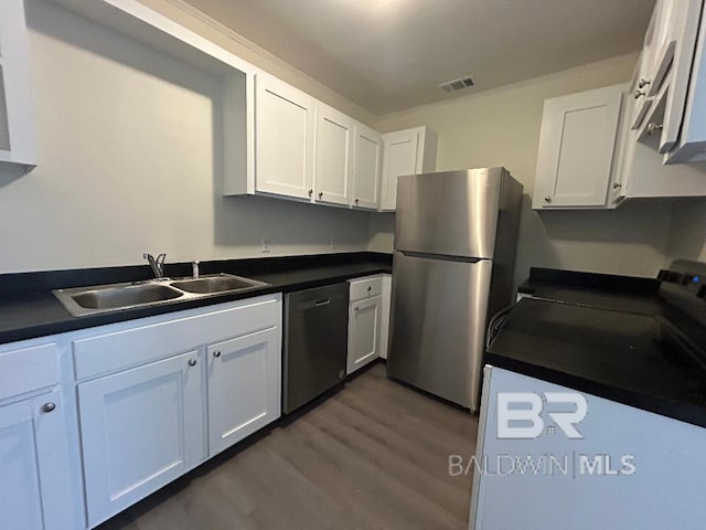 kitchen featuring appliances with stainless steel finishes, dark hardwood / wood-style floors, white cabinetry, and sink