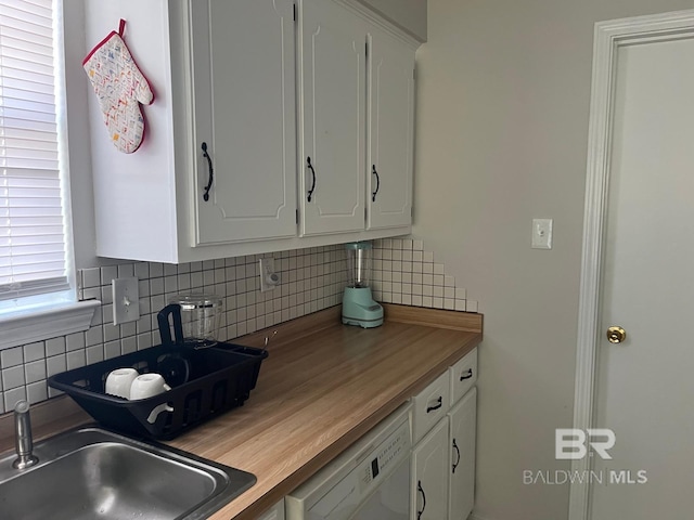 kitchen with butcher block countertops, sink, white dishwasher, white cabinets, and backsplash