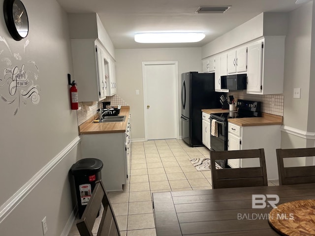 kitchen with sink, light tile patterned floors, tasteful backsplash, black appliances, and white cabinets