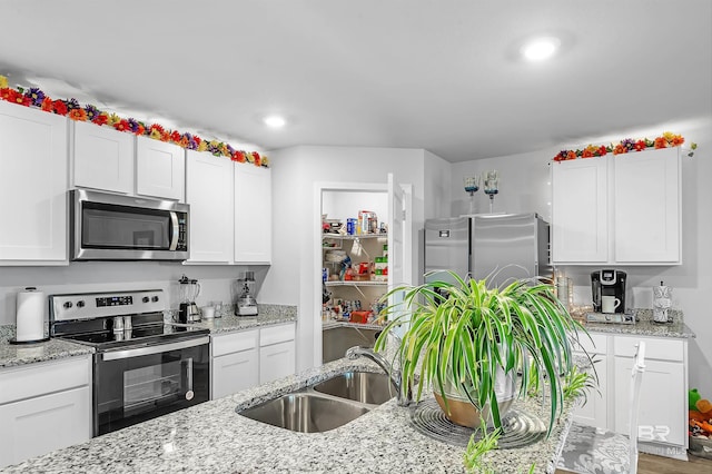 20770 Mercury Dr, Robertsdale, AL 36567 - kitchen with stainless steel appliances, white cabinetry, recessed lighting, and light stone countertops