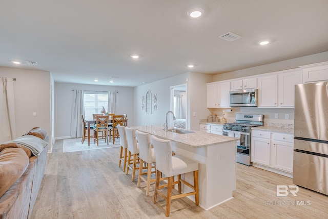 8242 Sycamore Way, Semmes, AL 36575 - kitchen featuring stainless steel appliances, recessed lighting, a kitchen island with sink, a breakfast bar, and white cabinets
