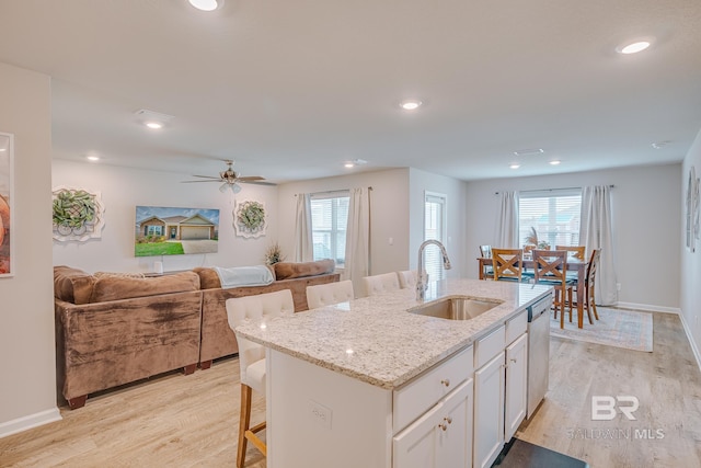 8242 Sycamore Way, Semmes, AL 36575 - kitchen featuring light wood-style floors, a kitchen bar, open floor plan, stainless steel dishwasher, and white cabinetry