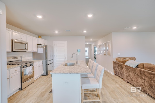 8242 Sycamore Way, Semmes, AL 36575 - kitchen featuring stainless steel appliances, a kitchen breakfast bar, open floor plan, light wood-type flooring, and white cabinetry