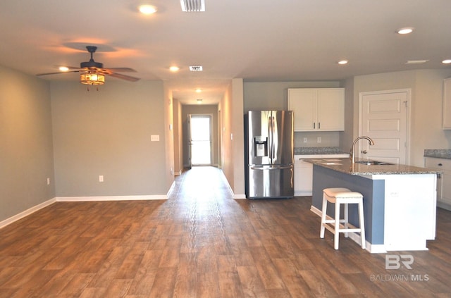 kitchen with dark stone counters, sink, a center island with sink, white cabinets, and stainless steel fridge with ice dispenser