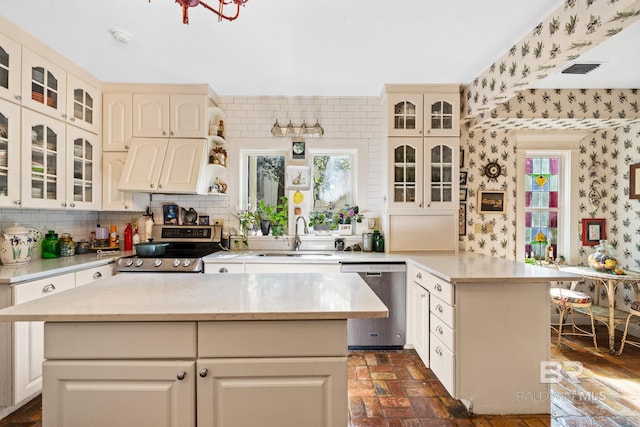 kitchen with cream cabinets, sink, a center island, and appliances with stainless steel finishes