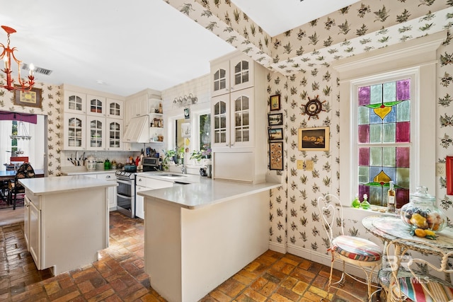 kitchen with white cabinetry, range with two ovens, kitchen peninsula, and tasteful backsplash