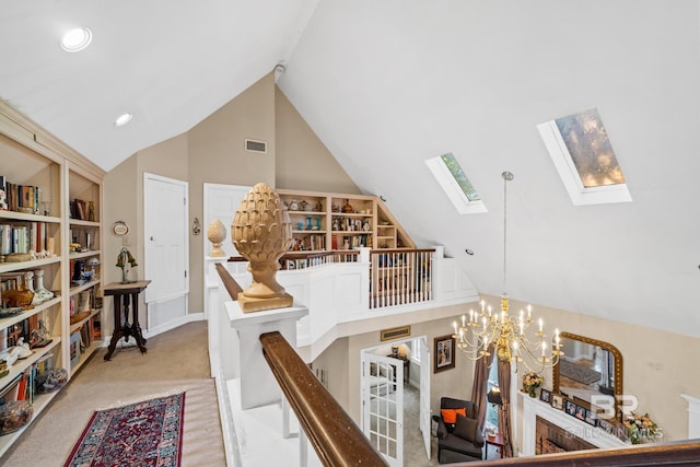 interior space with carpet flooring, a skylight, built in shelves, high vaulted ceiling, and a chandelier