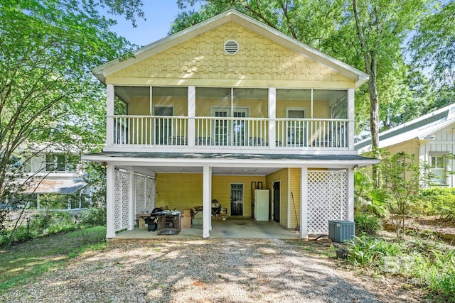 rear view of house with a carport, a sunroom, and central air condition unit